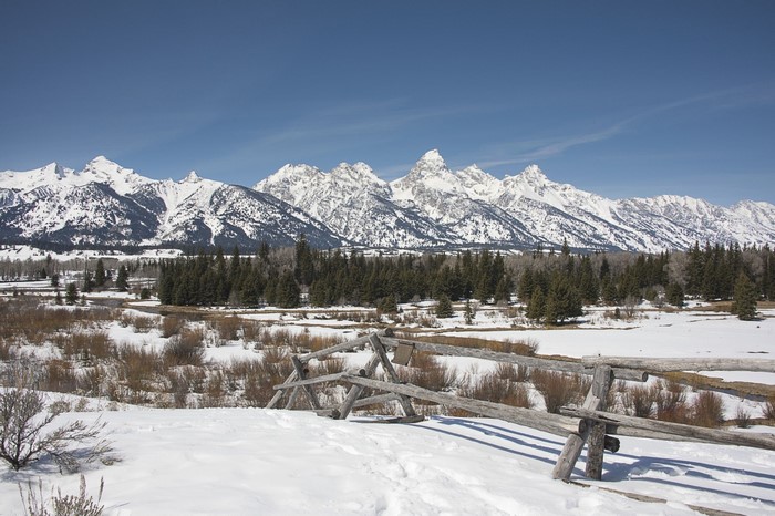 Snowy mountain range with wooden fence in foreground
