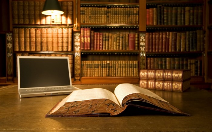Laptop and open book on a desk in a library