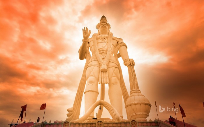 Giant Hanuman statue against an orange sky