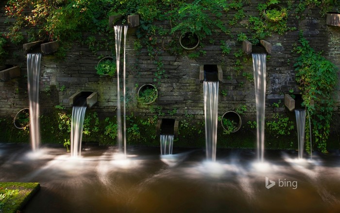 Waterfalls cascading down a stone wall into a stream