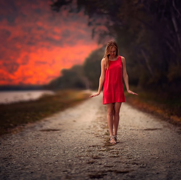 Woman in red dress walking on a path at sunset