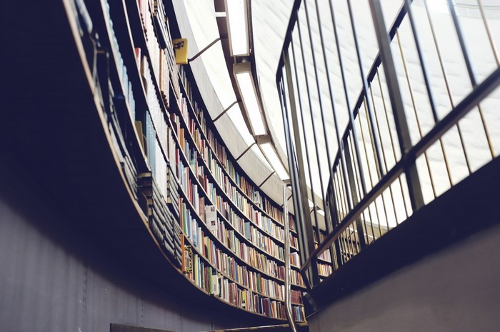 Curved library bookshelves with metal railing and lights
