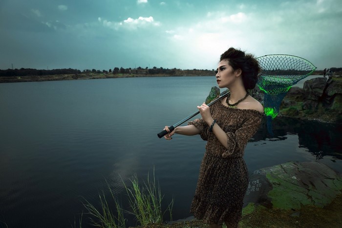 Woman with fishing net by a lake