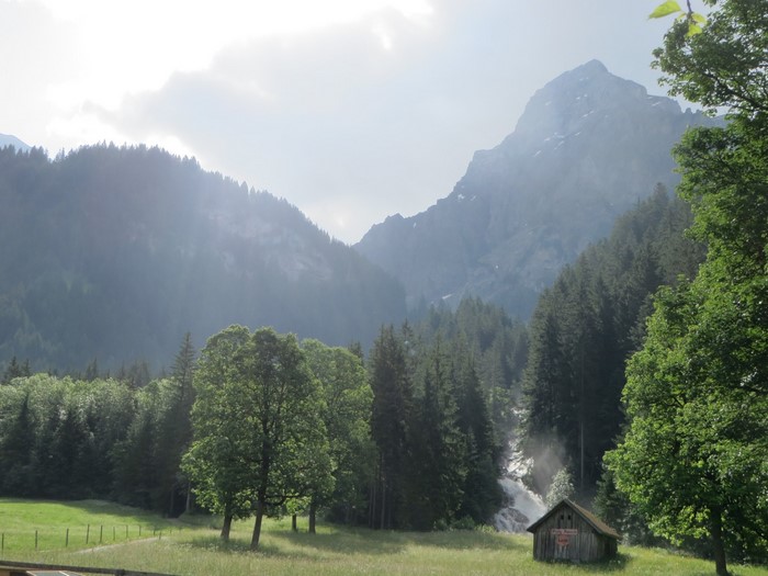 Wooden shack in a mountain valley with a waterfall