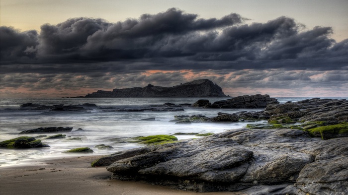 Rocky coastline with dark clouds over the ocean