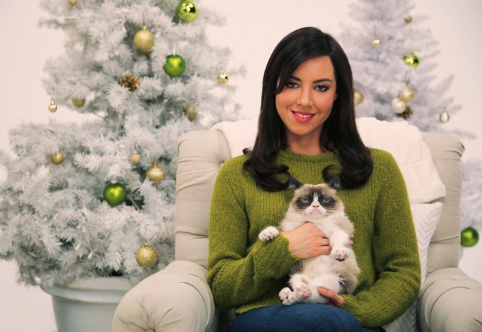 Aubrey Plaza holding Grumpy Cat with Christmas trees
