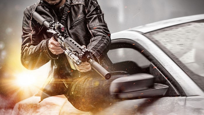 Man holding assault rifle near car