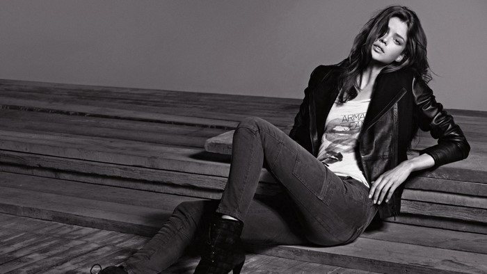 Woman in leather jacket and jeans sitting on wooden planks