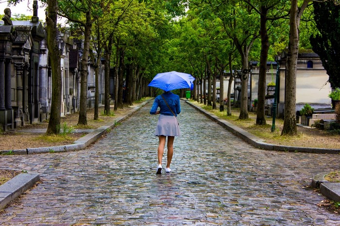 Woman with umbrella walking in Père Lachaise Cemetery, Paris