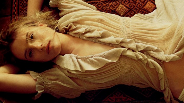 Woman in a ruffled dress lying on a patterned rug