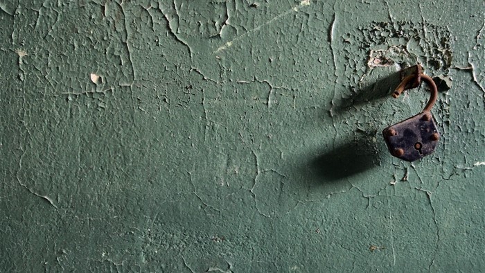 Old rusty padlock on a peeling green wall