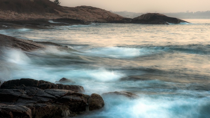 Waves crashing on rocky shore at sunset