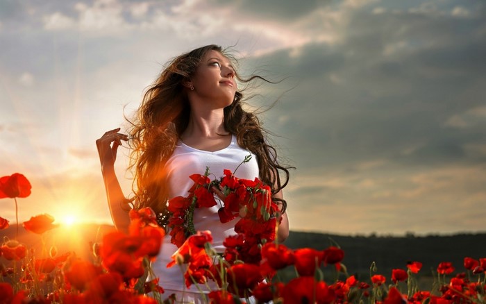 Woman in a poppy field at sunset