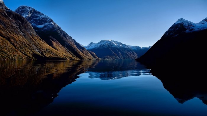 Mountains reflected in a calm lake under a clear blue sky