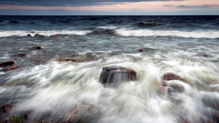 Waves crashing on rocky shore at dusk