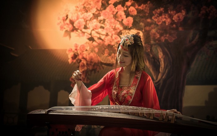 Woman in red playing a traditional string instrument