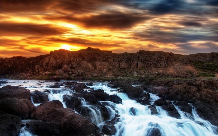 Rocky waterfall at sunset with dramatic clouds