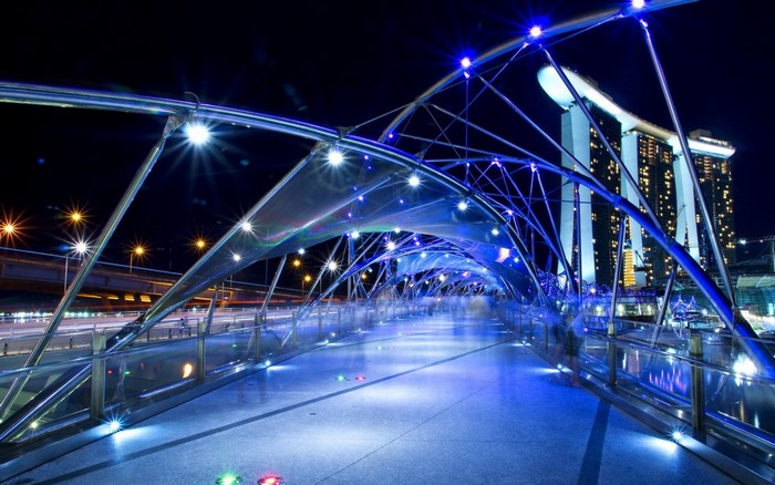 Helix Bridge illuminated at night with Marina Bay Sands in background
