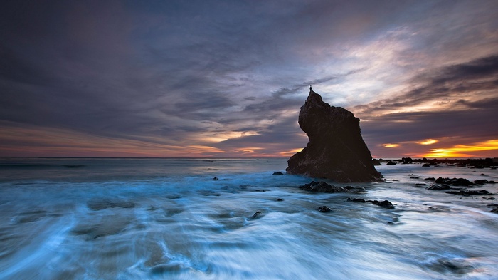 Person standing on a rock at sunset