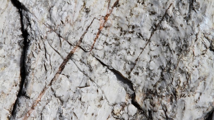 Close up of a textured rock surface with mineral veins