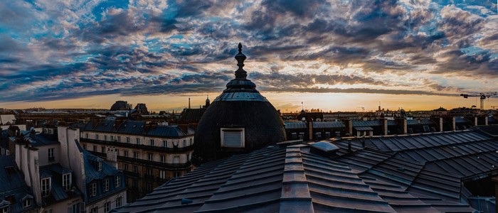 Cityscape at sunset with dramatic clouds over rooftops