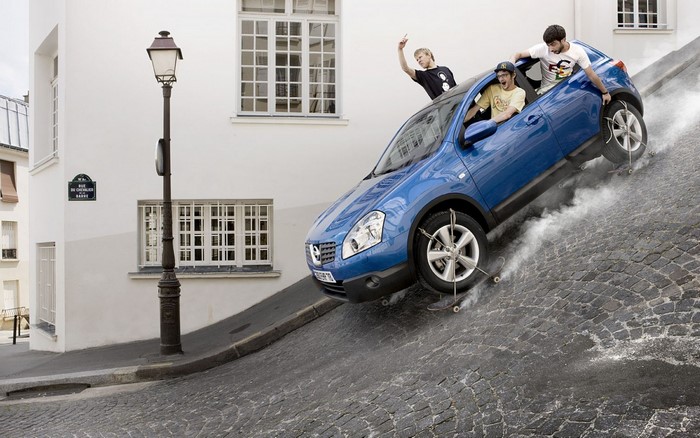 Men on skateboards in a blue car on a steep street