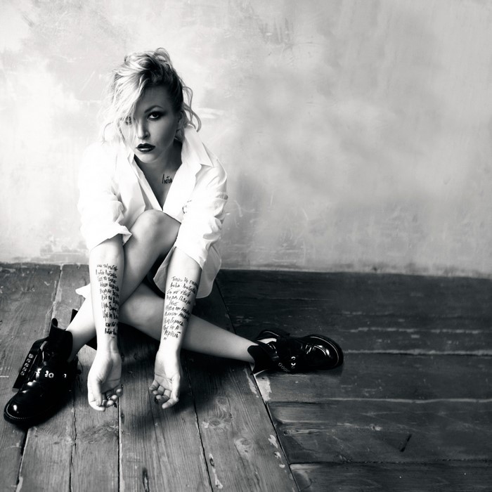 Woman with tattoos sitting on wooden floor