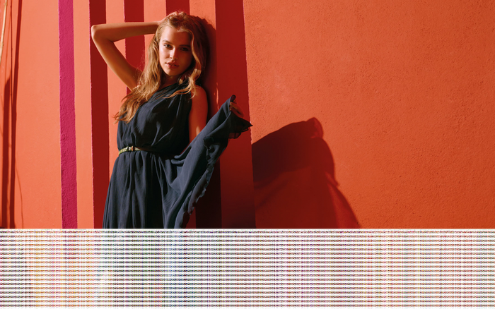 Tanya Mityushina in a dark dress against a striped wall