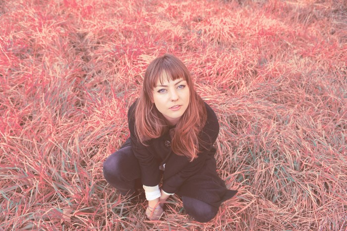 Angel Olsen sitting in a field of grass