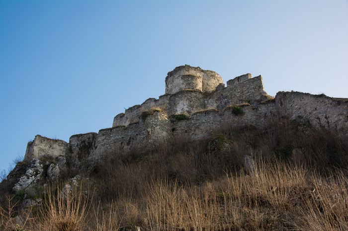 Ruined castle on a grassy hill under a clear blue sky