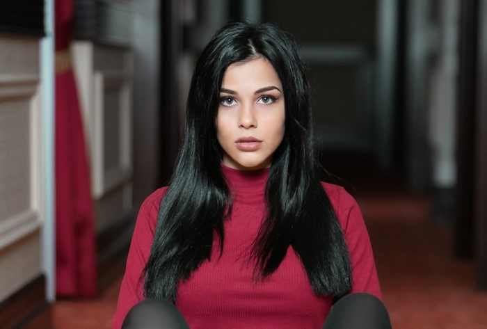 Woman with long black hair wearing a red turtleneck