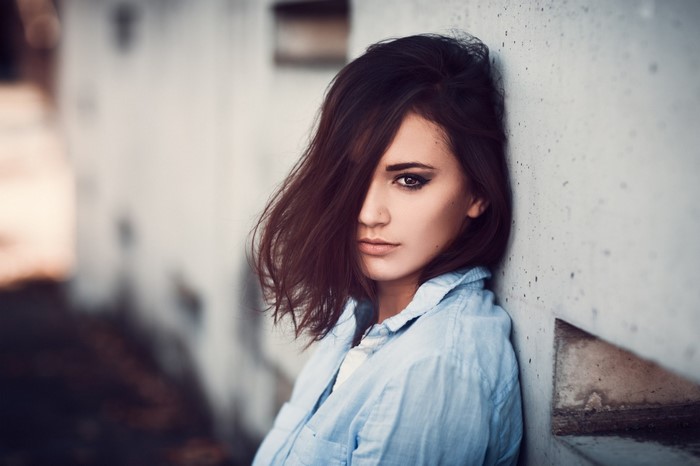 Woman with dark hair leaning against a wall