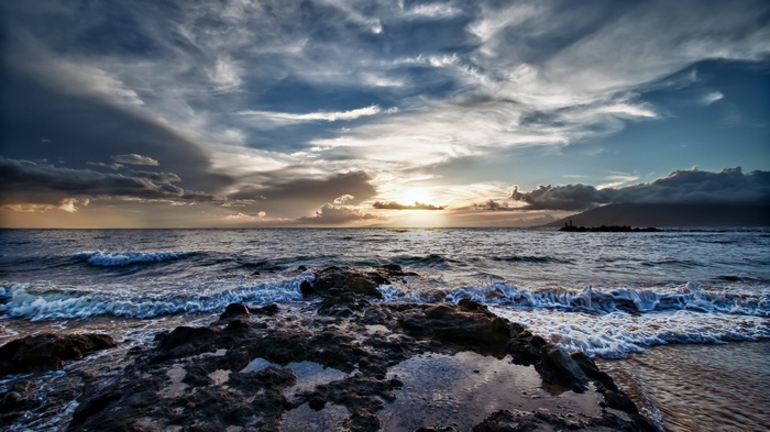 Ocean waves crashing on rocky shore at sunset