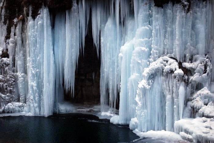 Frozen waterfall with icicles and a dark pool of water