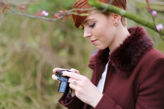 Woman with short red hair holding a camera