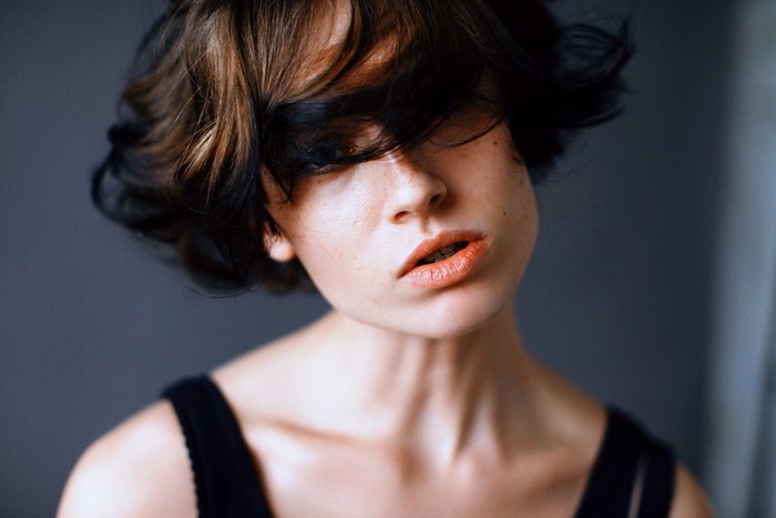 Woman with short, dark and brown hair covering her face