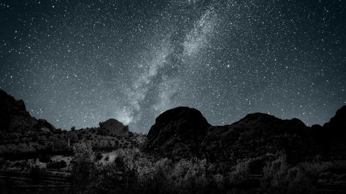 Milky Way over dark mountains and trees