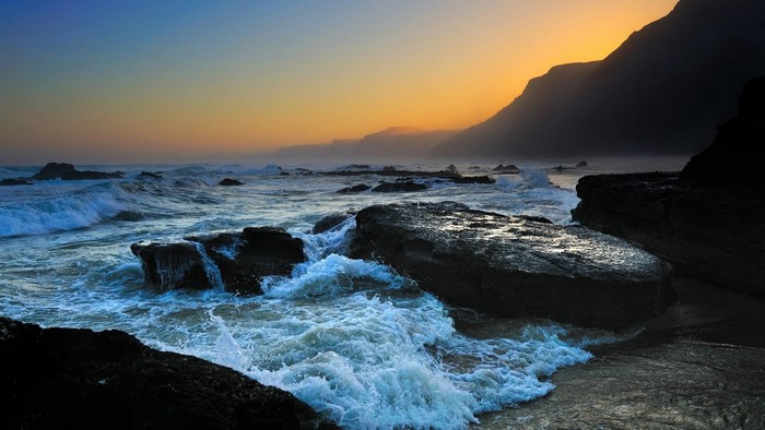 Sunset Over Rocky Ocean Shore with Waves