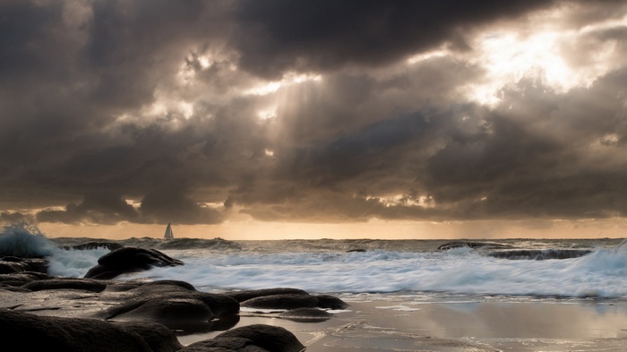Sailboat on stormy sea with dramatic clouds and waves