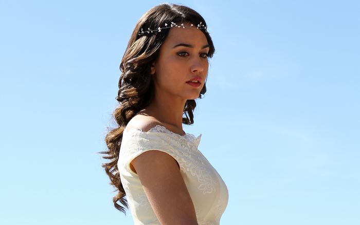 Megan Montaner wearing a white dress with a floral headband