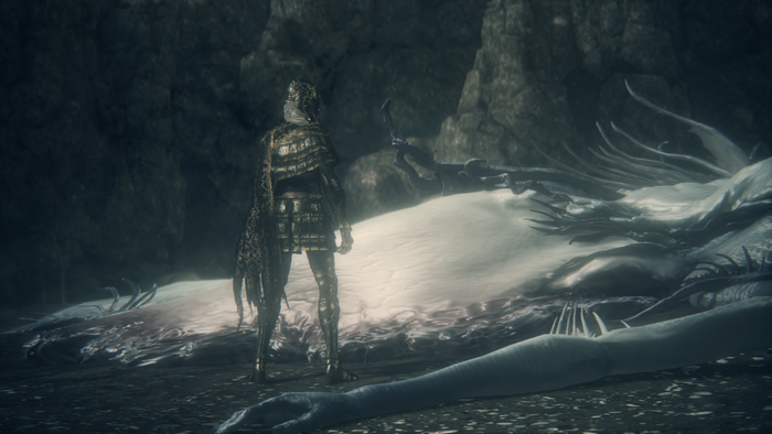 Character in armor standing near a large corpse in Bloodborne
