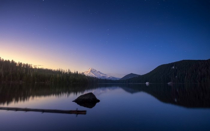 Snowy mountain peak reflected in a calm lake at dusk