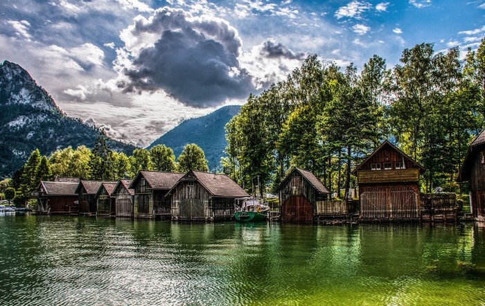 Boathouses on a lake with mountains and trees