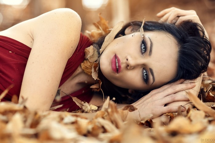 Brunette Woman Lying in Autumn Leaves Close-Up