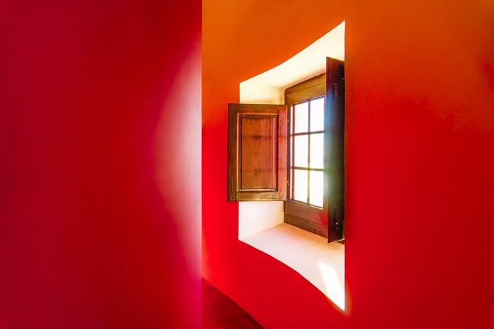 Interior view of a red room with an open wooden window