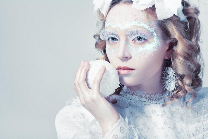 Woman with winter-themed makeup holding a snowball