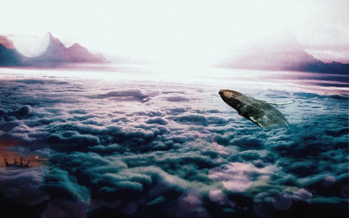 Whale breaching through clouds above mountains