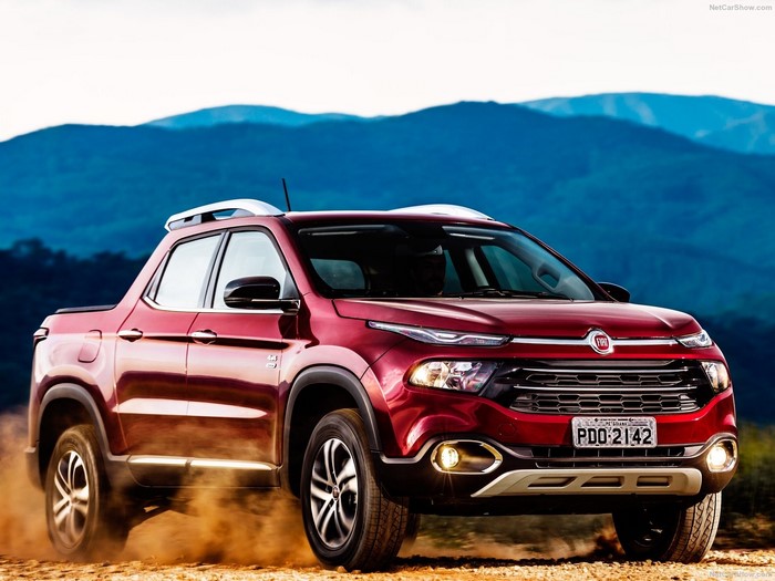 Red Fiat Toro pickup truck driving on dirt road