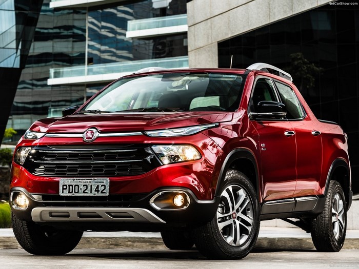 Red Fiat Toro pickup truck parked in front of modern buildings