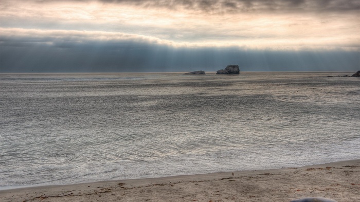 Ocean waves and rock formations under cloudy sky